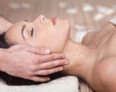 Happy woman receiving head massage over bamboo mat