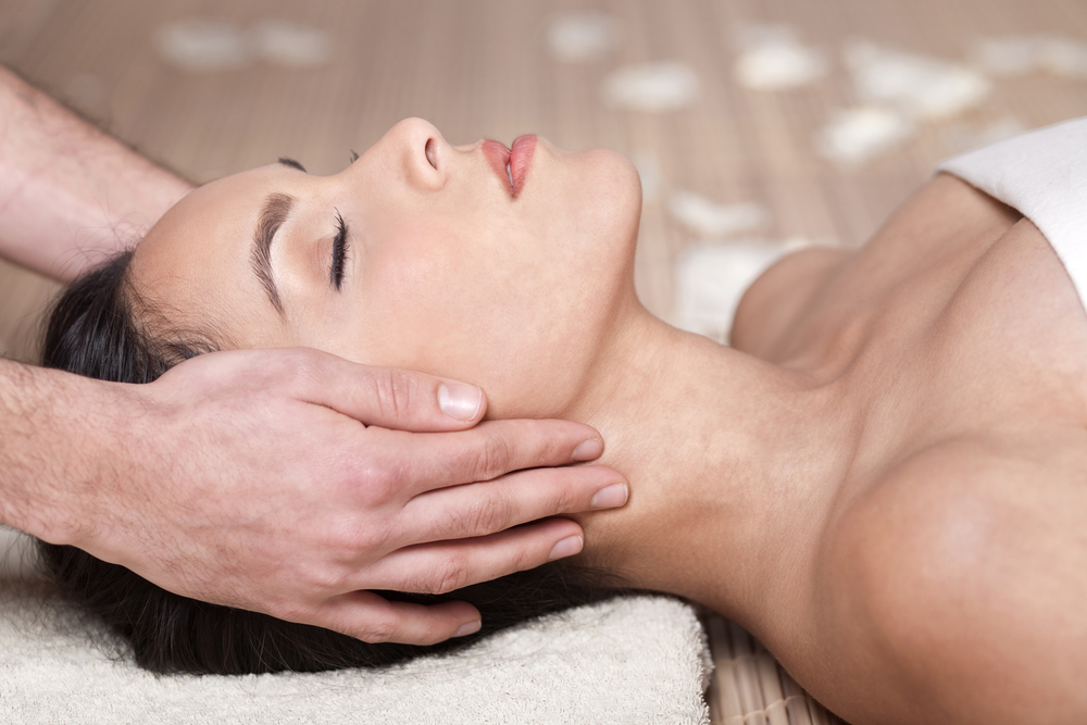 Happy woman receiving head massage over bamboo mat