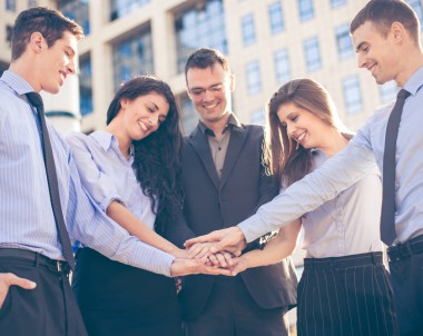 Group of young business people standing in front of the company with folded hands, motivating for new business wins.