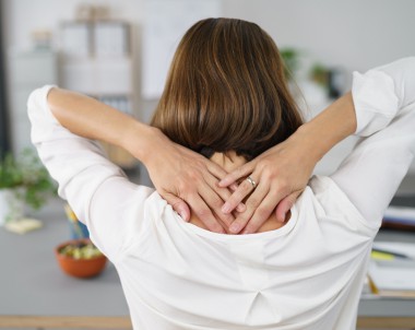 Close up Rear View of a Tired Businesswoman Holding her Nape with Two Hands.